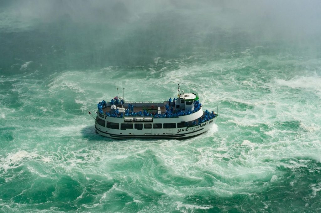 A boat with tourists on it visiting the Niagara Falls. 