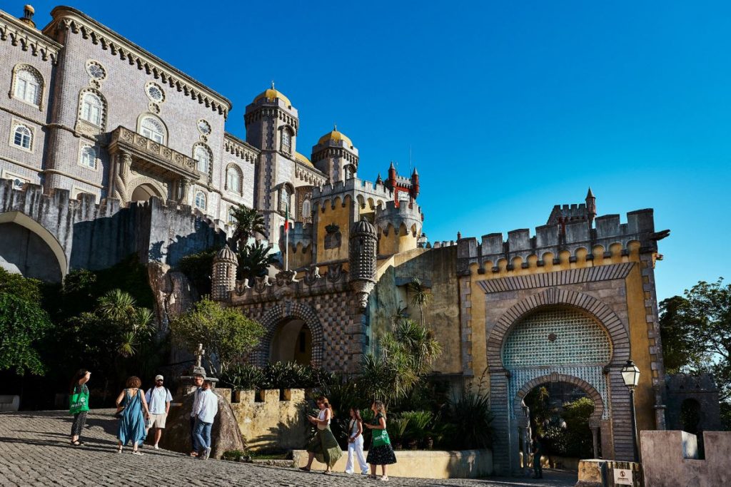 People walking up a hill to Pena Palace. 