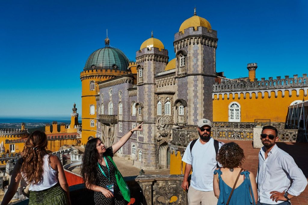 A group of people standing outside of Pena Palace. 