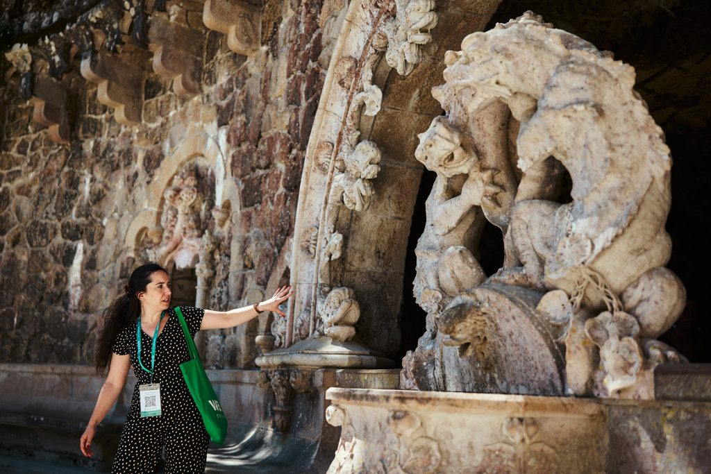 A woman pointing at a fountain at Quinta da Regaleira.