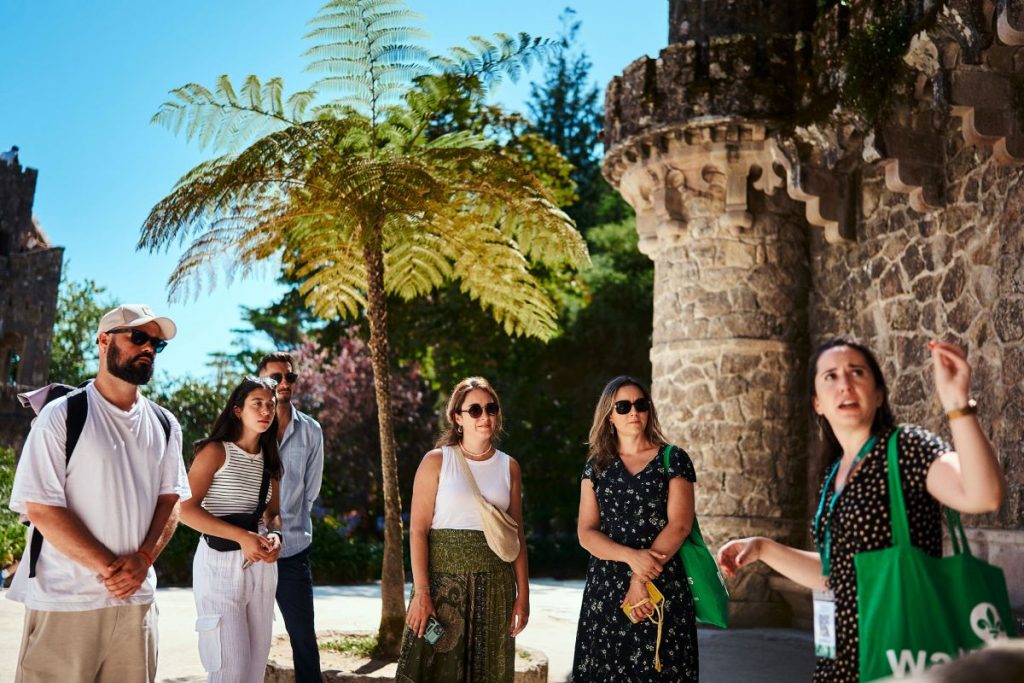 A group of people standing in Quinta da Regaleira's gardens looking at a fountain.