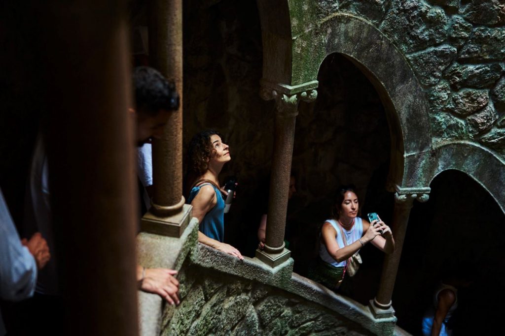 People on the staircase of the Quinta da Regaleira tunnels taking photos.