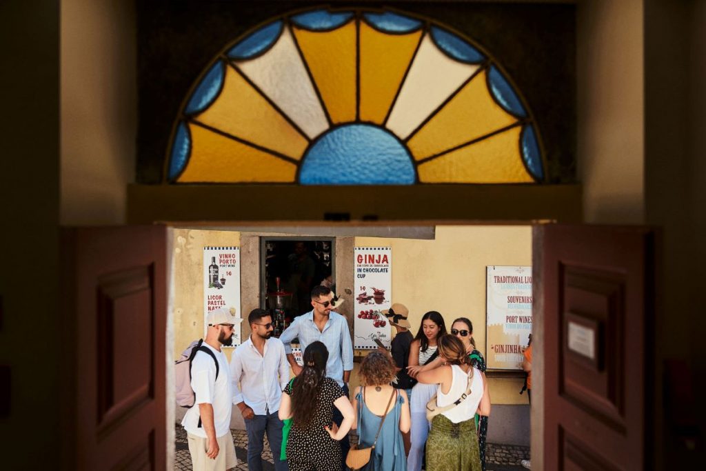 A group of people standing outside of a ginja shop in Portugal.