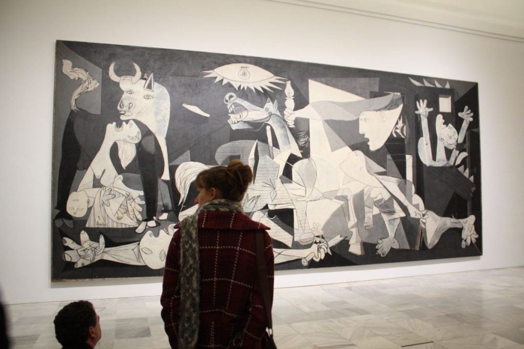 People looking at a Picasso painting in Madrid. 