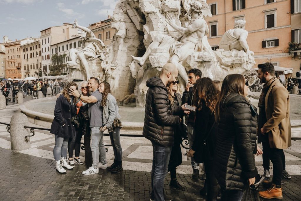 People taking photos near a fountain in Rome. 